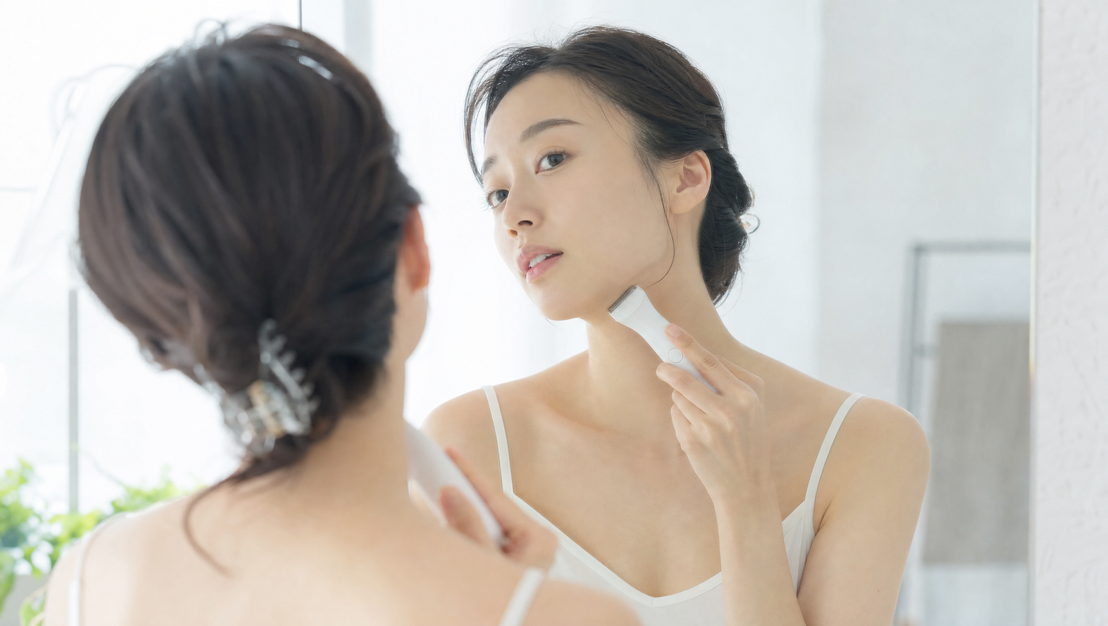 電動フェイスシェーバーで首元の産毛を整える女性